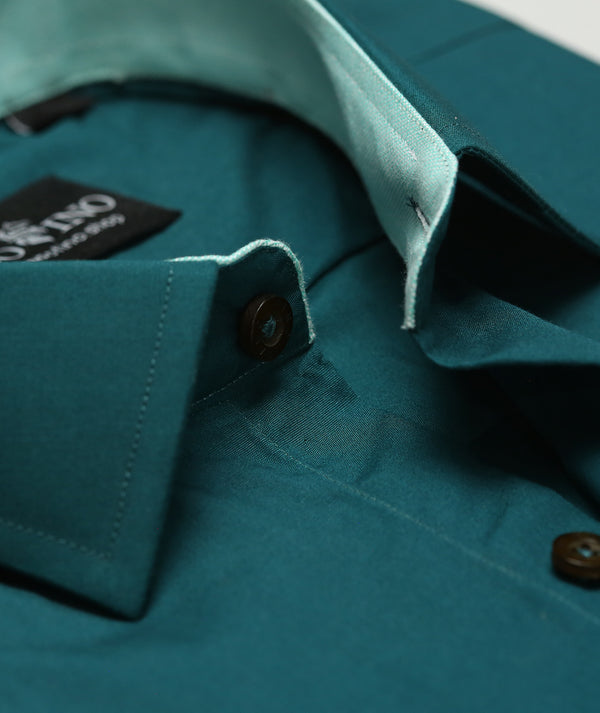 Close-up of a teal shirt with a brand label on a matching background